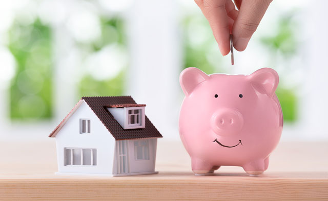 Small house and piggy bank getting a coin dropped in it